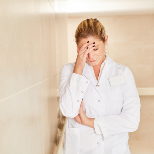 Overworked nurse with hand on head experiencing burnout